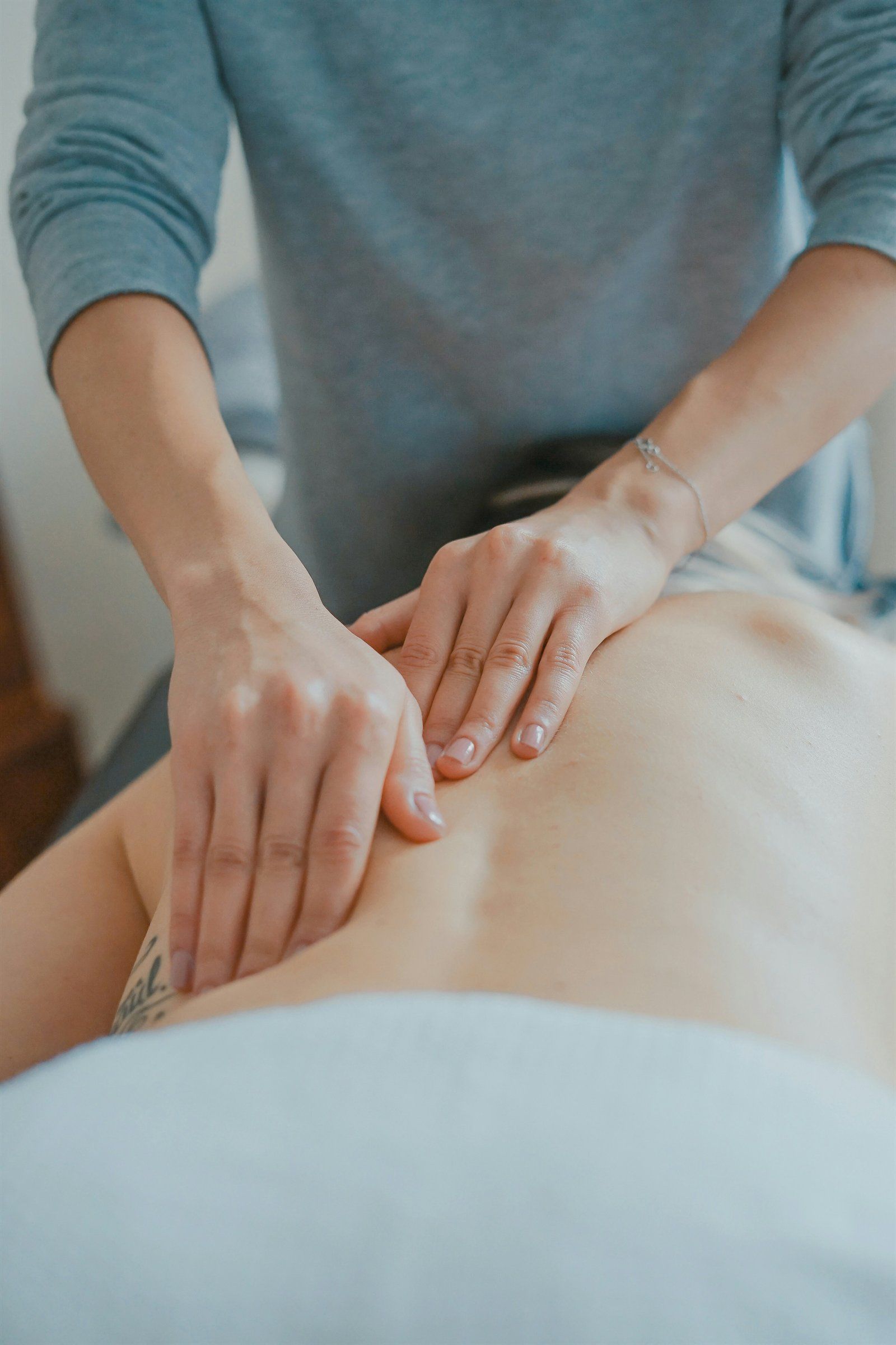 Mains posées délicatement sur le dos d'une personne pendant une séance de microkinésithérapie