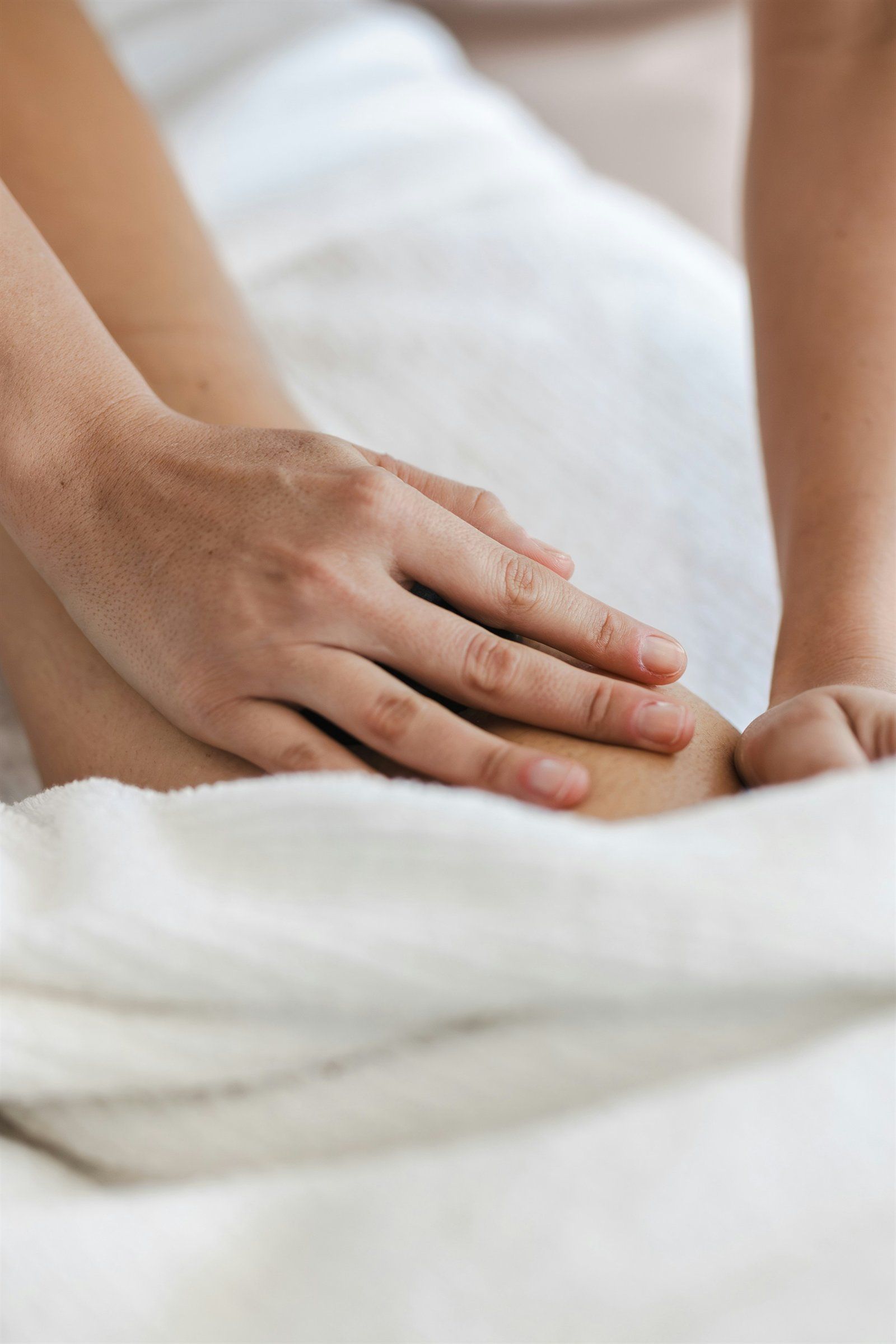 Main posée avec douceur sur une jambe recouverte d'une serviette blanche