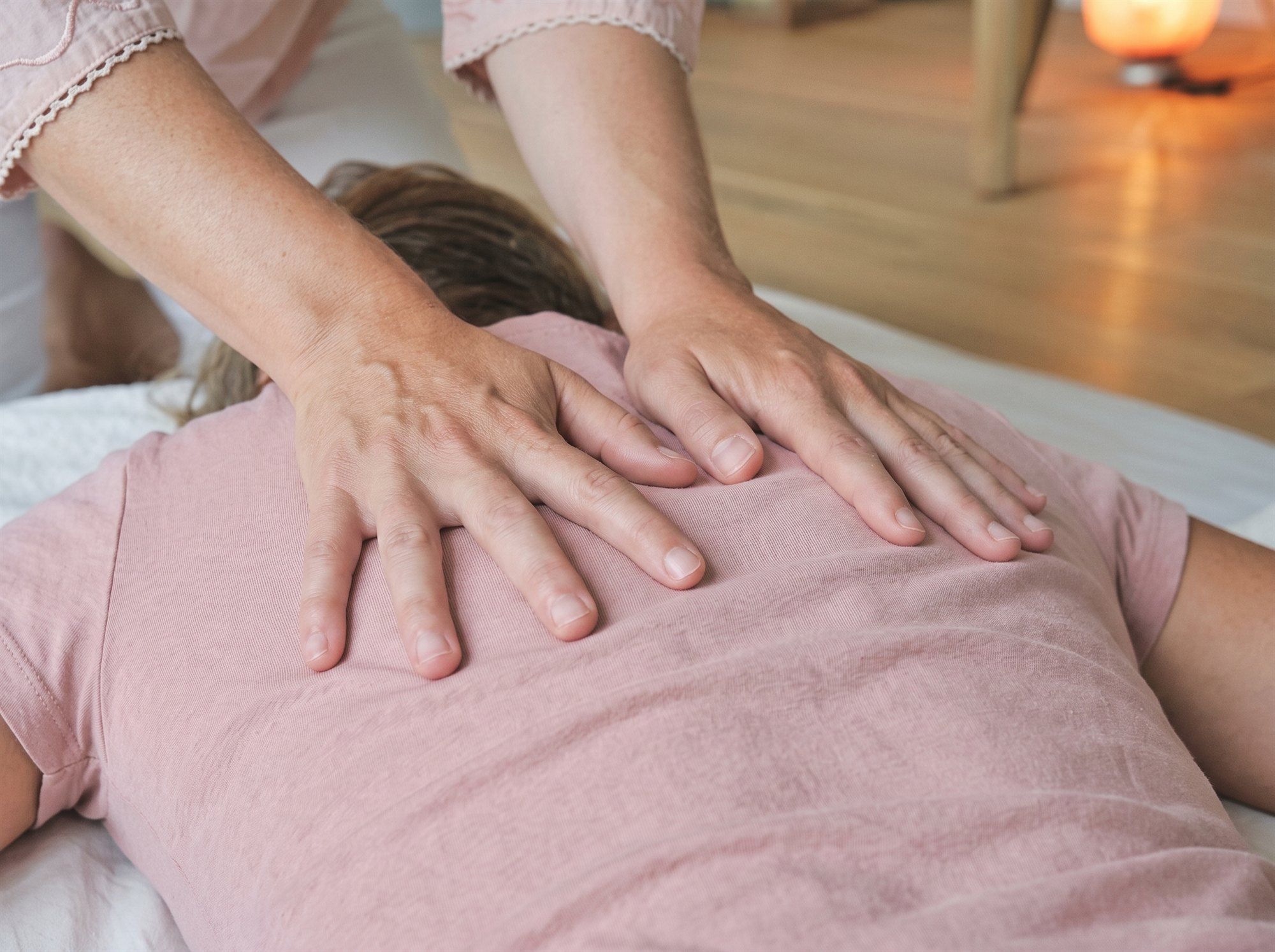 Mains posées à plat sur le dos d’une personne habillée, pendant une séance de microkinésithérapie